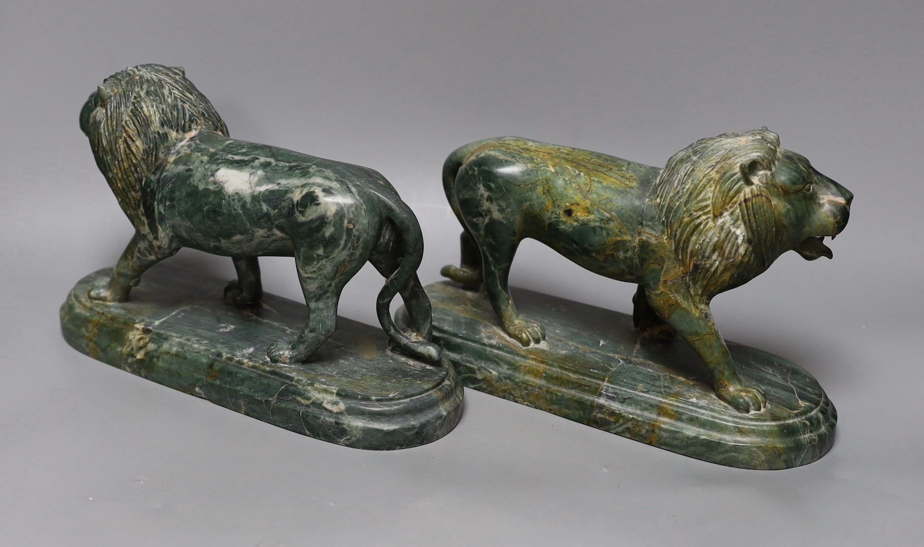 A pair of carved green serpentine models of lions rampant, 24 cms wide